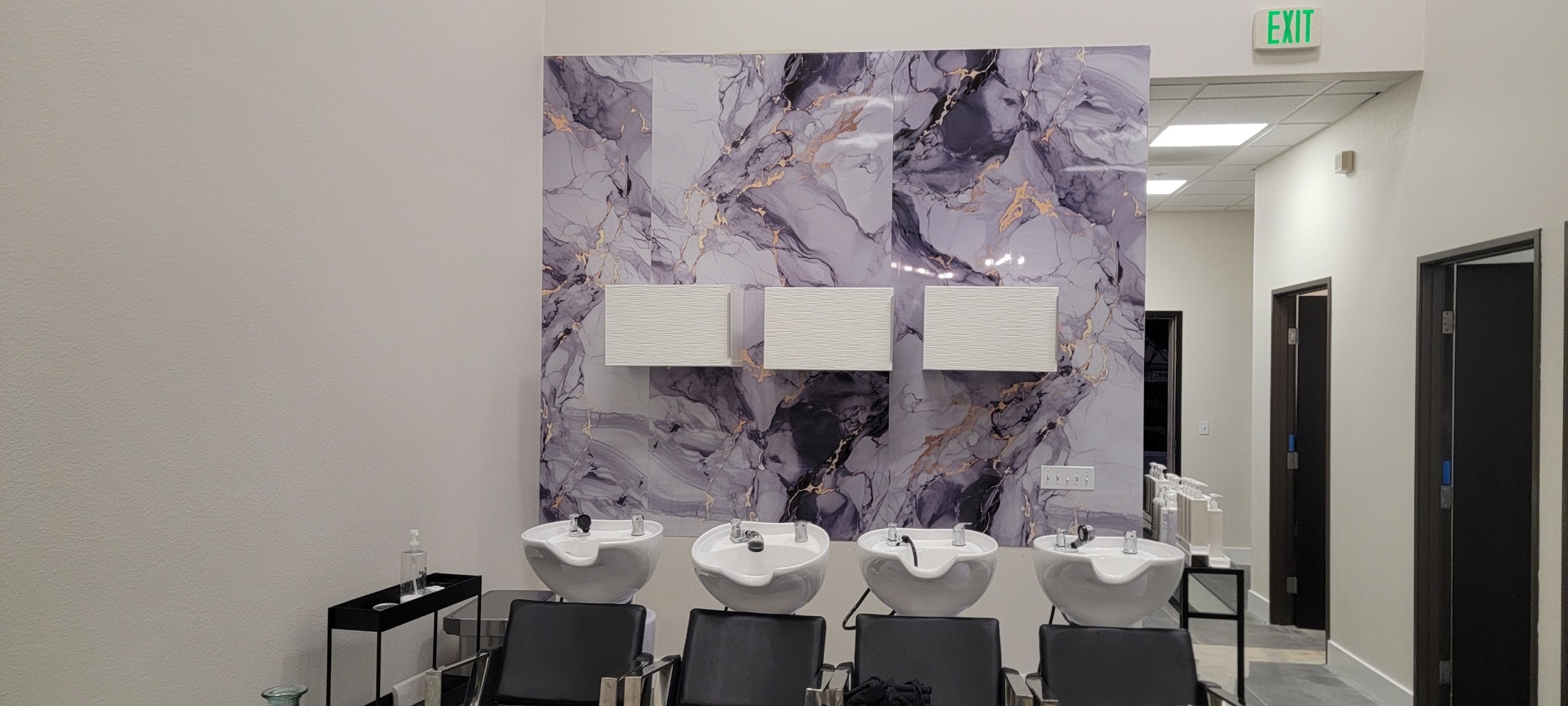 Commercial salon wash stations with marble-look feature wall.