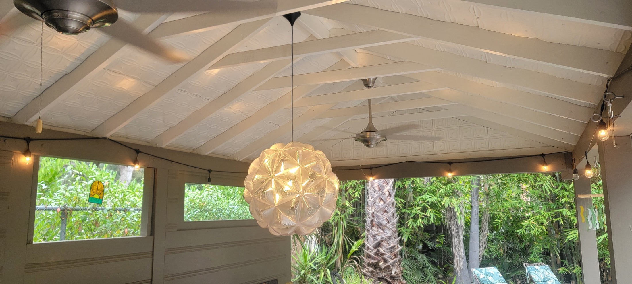 Covered patio structure with exposed beams, pendant light, and outdoor seating.