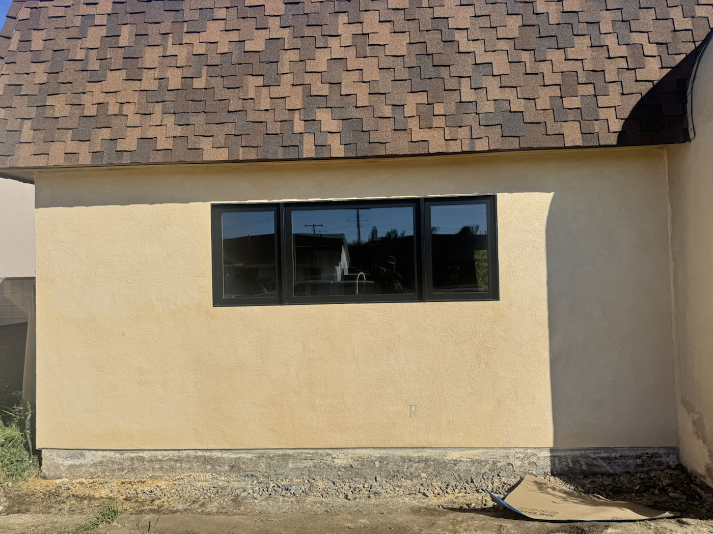 Exterior stucco wall with new black-framed windows.